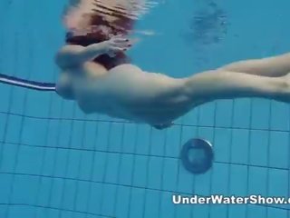 Redheaded chica nadando desnuda en la piscina